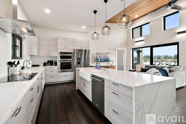 A modern kitchen with white cabinets and a marble island.