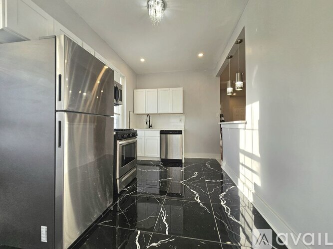 A modern kitchen with a marble floor and stainless steel appliances.