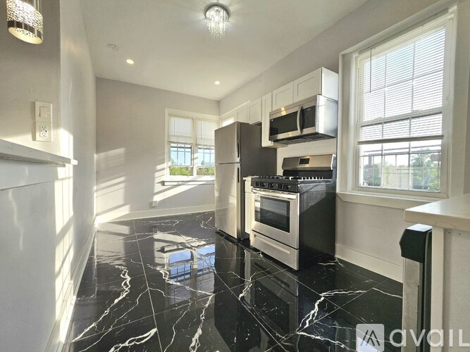 A kitchen with black marble countertops and stainless steel appliances.