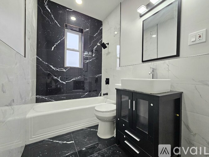 A bathroom with a black and white marble floor and a white bathtub.