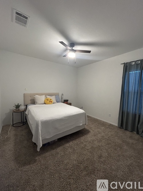 A bedroom with a white bed and a ceiling fan.