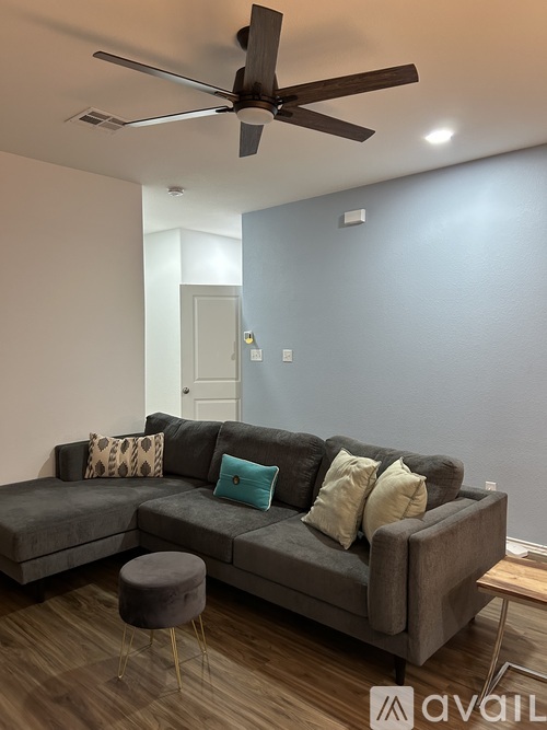 A living room with a grey couch and a ceiling fan.