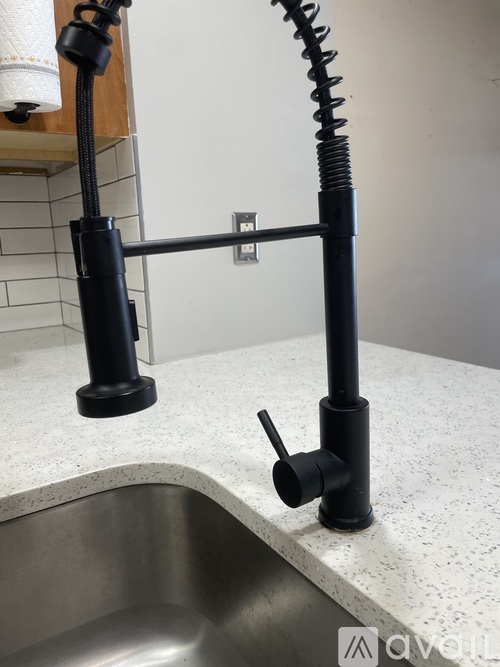 A kitchen sink with a black pipe and a roll of toilet paper.