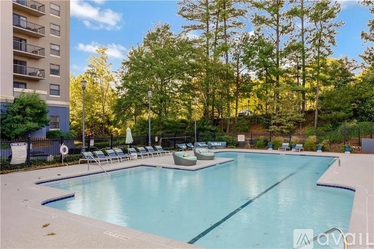 A large outdoor swimming pool surrounded by trees and lounge chairs.