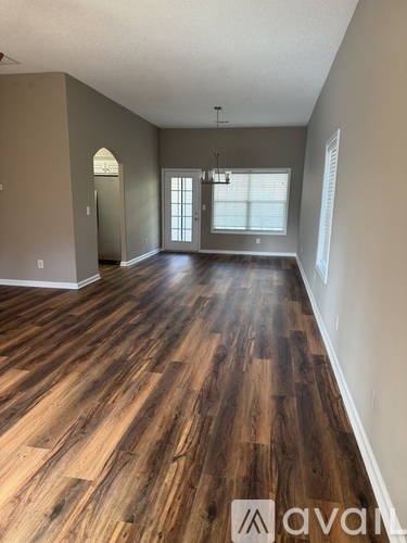 A spacious room with wooden flooring and a large window.