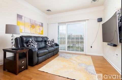 A living room with a black leather couch and a painting on the wall.