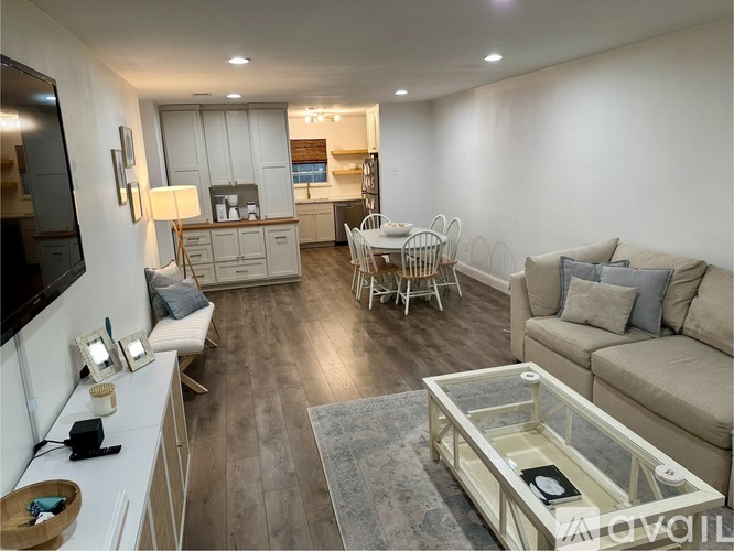 A modern living room with a glass coffee table and a television on the left side.