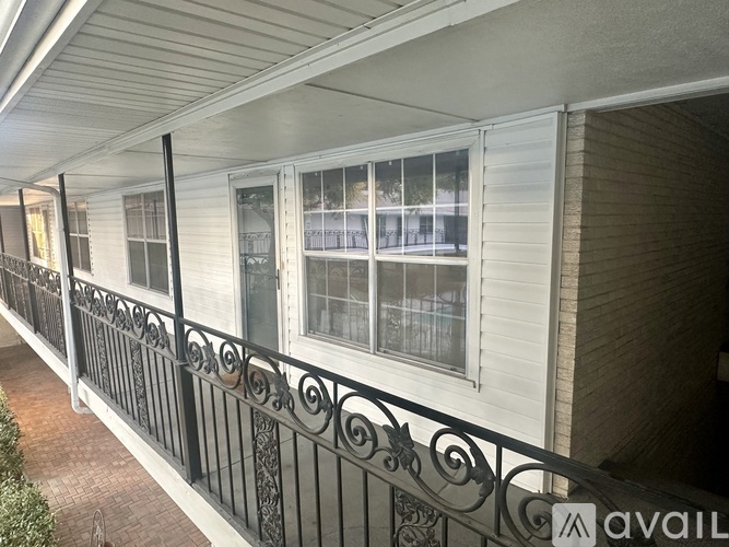 A balcony with a metal railing and a window overlooking a building.