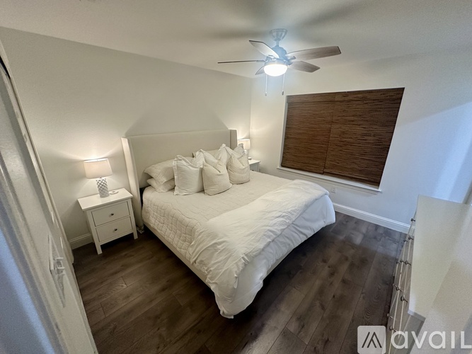 A bedroom with a bed, nightstand, and window with blinds.