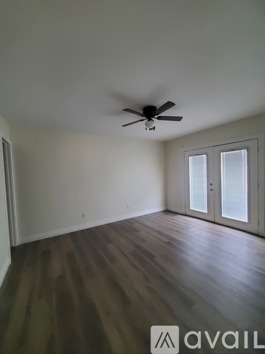 A room with a ceiling fan and wooden flooring.