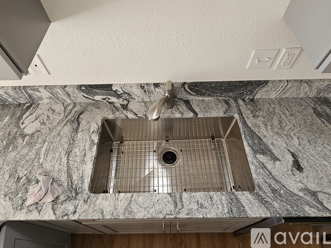 A kitchen sink with a marble countertop and a metal drain.