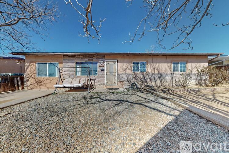 A house with a gravel driveway and a tree in front.