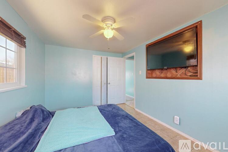 A bedroom with a bed, ceiling fan, and a mirror on the wall.