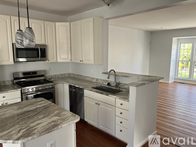 A kitchen with white cabinets and a marble countertop.