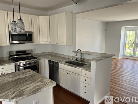 A kitchen with white cabinets and a marble countertop.