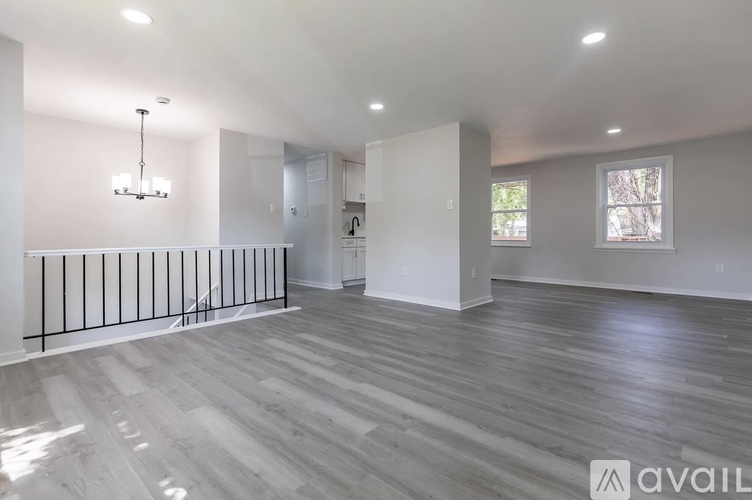 A spacious room with wooden flooring and a chandelier.