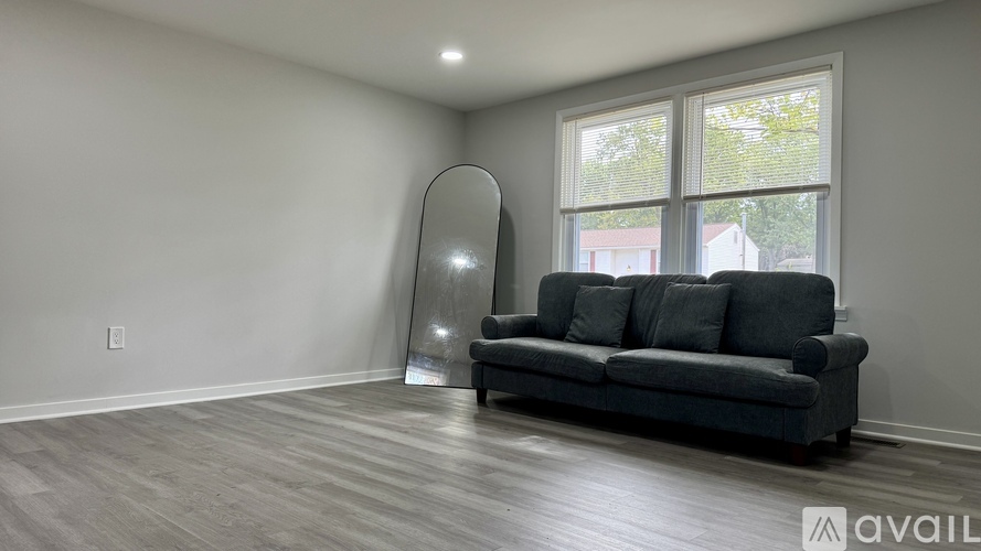 A living room with a grey couch and a mirror.