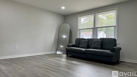 A living room with a grey couch and a mirror.