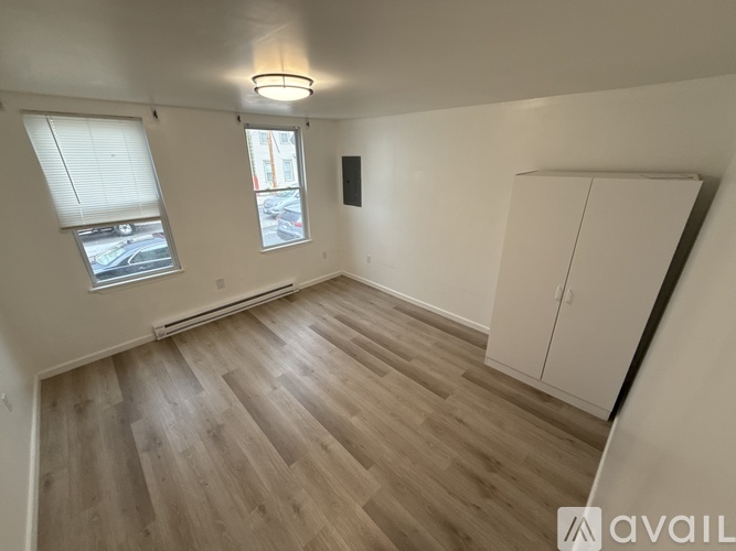 A room with wooden flooring and a window with blinds.