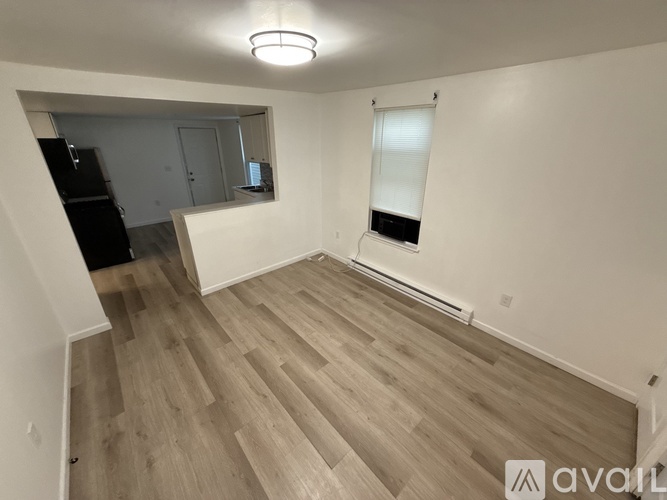 A room with wooden flooring and a window with blinds.