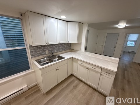 A kitchen with white cabinets and a stone backsplash.