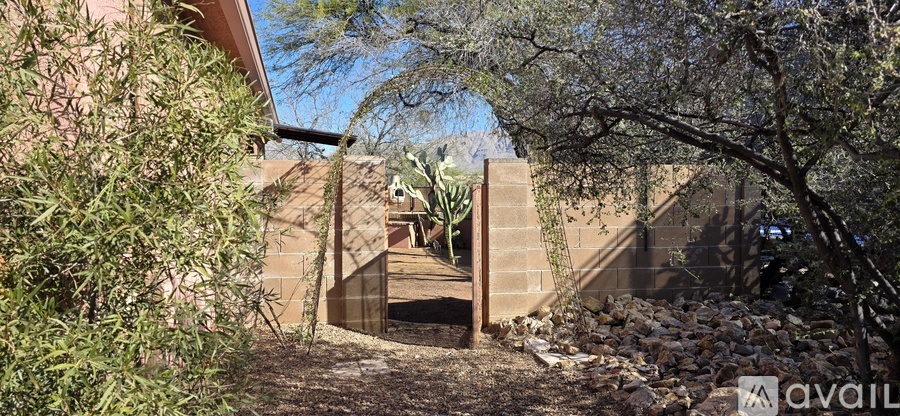 A house with a brown exterior and a gate is surrounded by greenery.