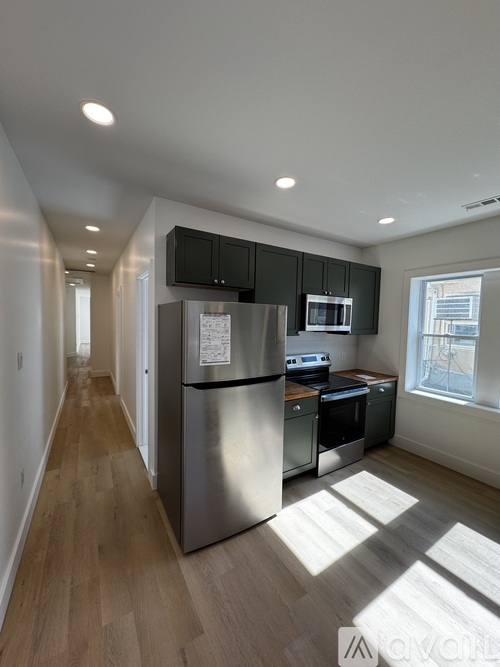 A kitchen with a stainless steel refrigerator and wooden floors.