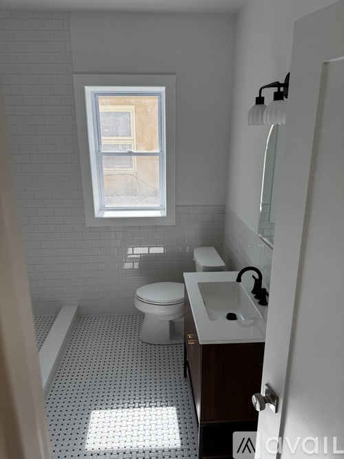 A white toilet is in a bathroom with a window above it.