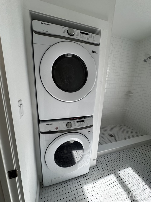 A white Samsung washing machine and dryer in a small laundry room.