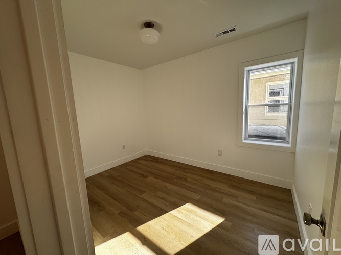 A room with wooden flooring and a window showing a building outside.