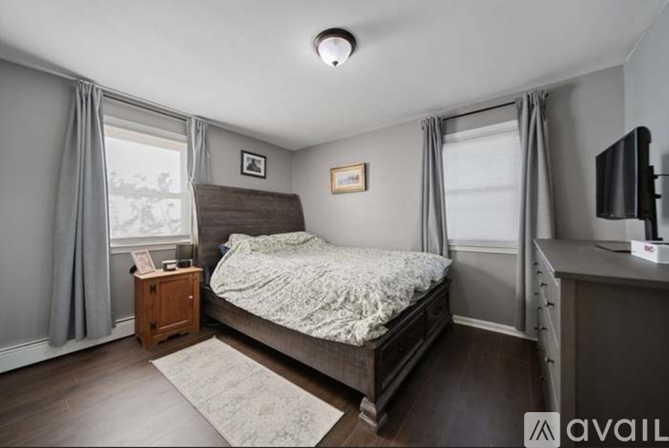 A bedroom with a bed, nightstand, and window with curtains.