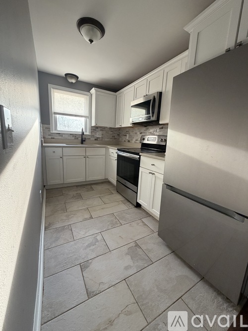 A kitchen with a refrigerator, microwave, oven, and sink.