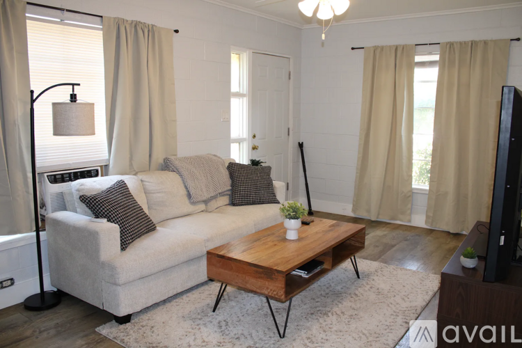 A living room with a white couch, a wooden coffee table, and a television.