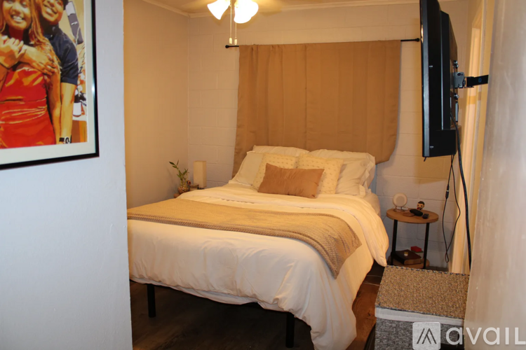 A bedroom with a large bed and a flat screen TV mounted on the wall.