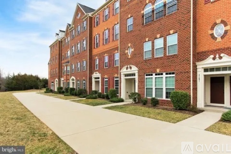 A brick building with a clock on the side and a driveway in front.