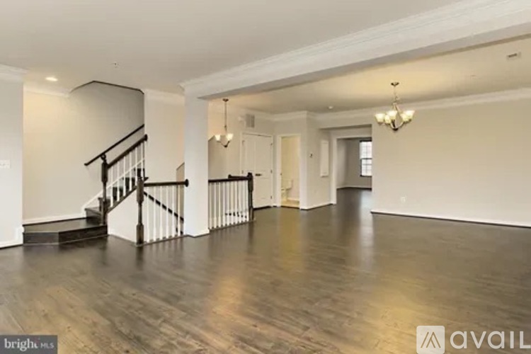 A spacious room with a staircase and a chandelier.
