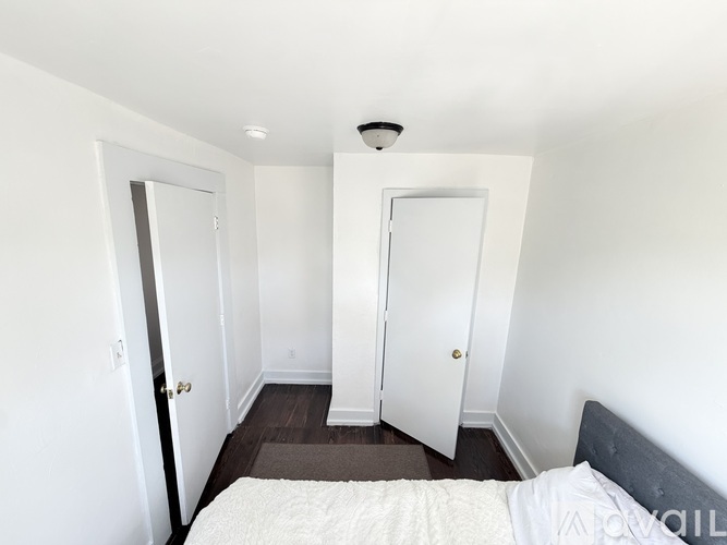 A small, empty room with white walls and a wooden floor.