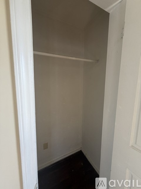 A small, empty room with white walls and a wooden floor.