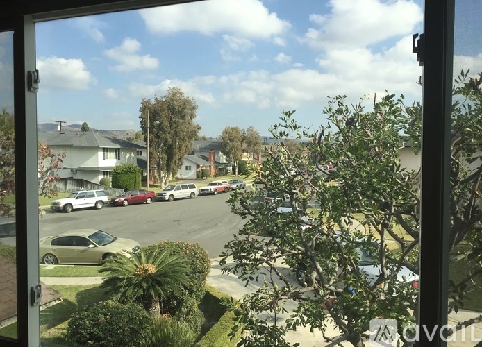 A view from a window looking out at a street with cars and houses.