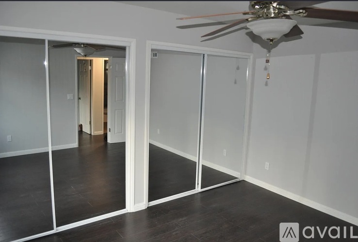 A room with a ceiling fan and sliding glass doors.