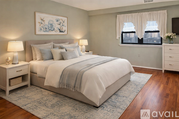 A bedroom with a large bed, two nightstands, and a painting on the wall.