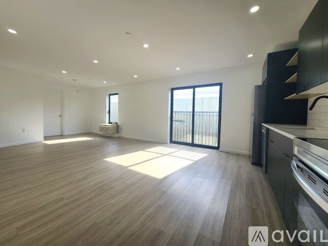 A spacious room with wooden flooring and a large window.