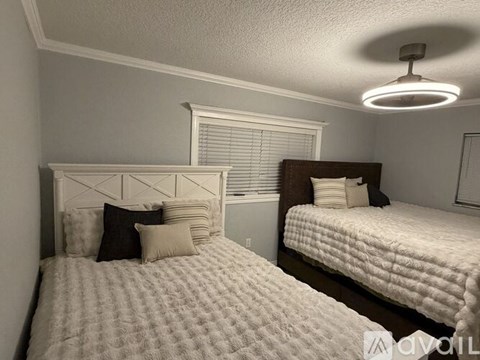 Two beds with pillows and a ceiling fan in a room.