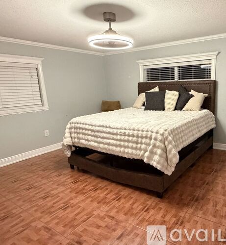 A bedroom with a bed, pillows, and a window with blinds.