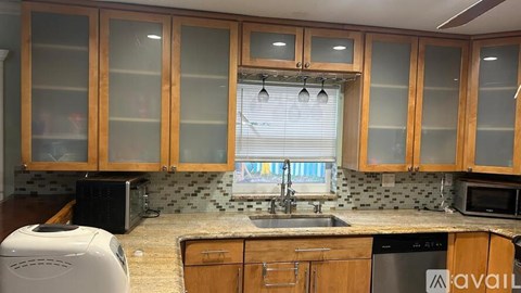 A kitchen with wooden cabinets and a black microwave.
