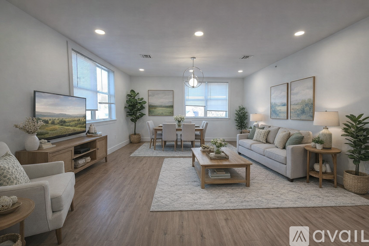 A well-lit living room with a white sofa, wooden coffee table, and a large painting on the wall.