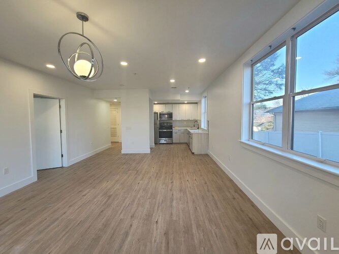 A spacious room with wooden flooring and a large window.