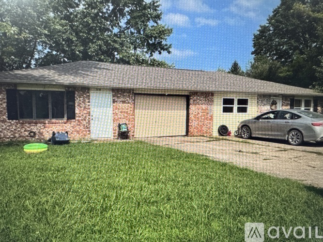A house with a grey car parked in front.