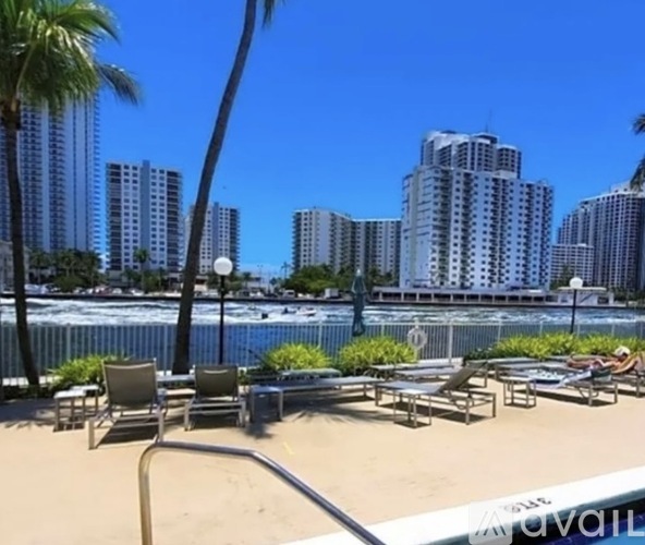 A sunny day at the beach with chairs and palm trees.