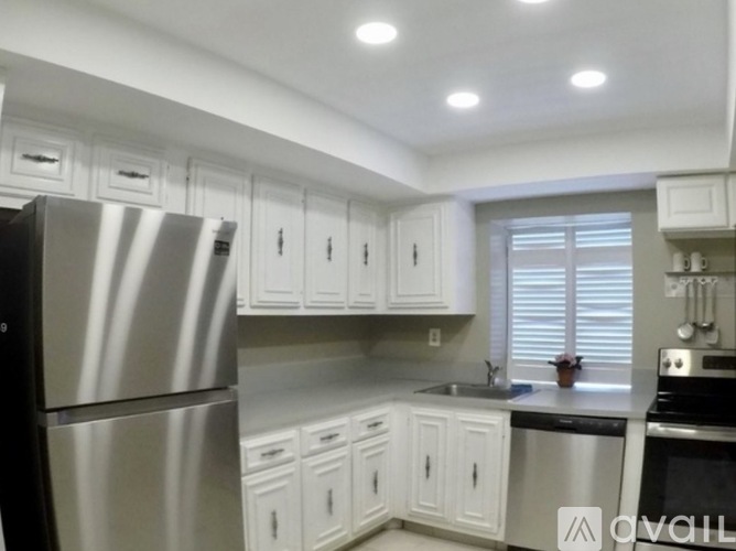 A kitchen with white cabinets and a stainless steel refrigerator.